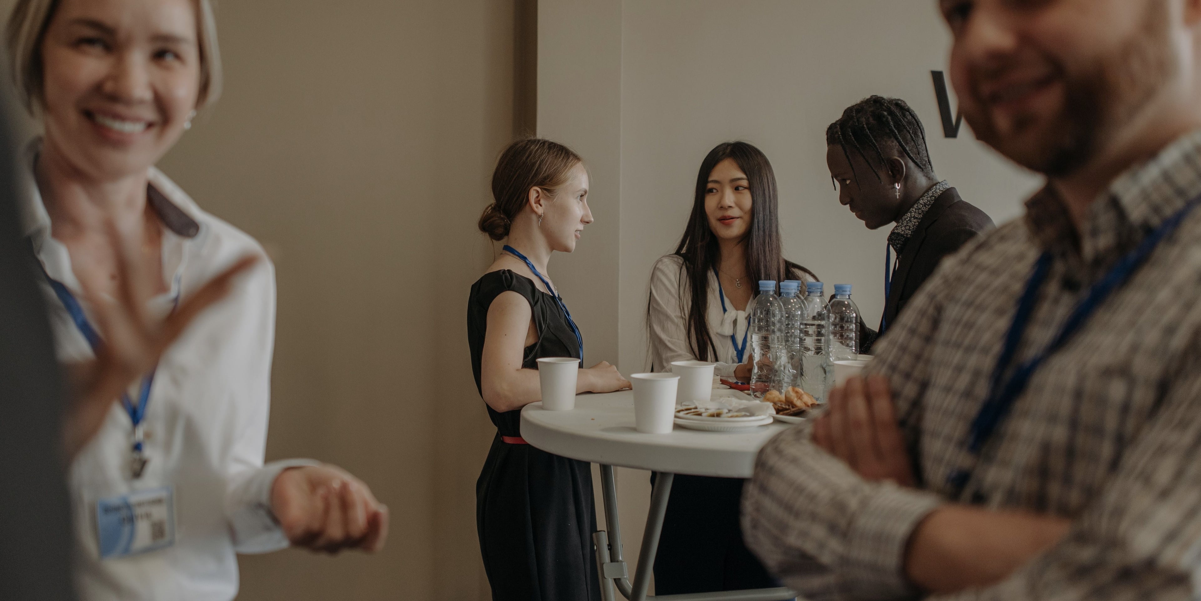 Gruppe af mennesker på konference eller møde omkring bord med vand og snacks